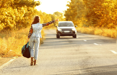 Fototapeta premium Young woman with backpack hitchhiking on road