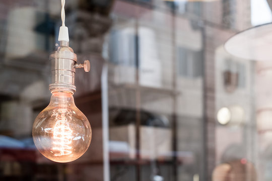 Decorative old edison style light bulb against blurred urban scene reflection