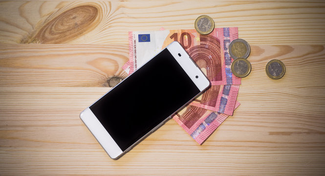 Smartphone und Geldscheine auf Holzuntergrund