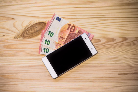 Smartphone und Geldscheine auf Holzuntergrund