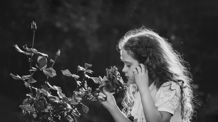 Little girl breathe scent of rose flowers. Black and white portr