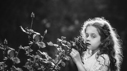 Little girl breathe scent of rose flowers. Black and white portr