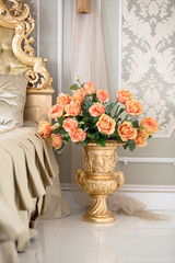 Luxury stylish bright light interior of apartment decorated by golden vase with flowers. Nobody inside room. Bedroom.