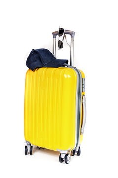 Travel yellow bag with cap and sunglasses on white background.