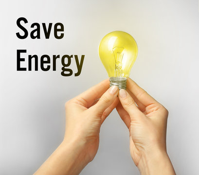 Female hands holding light bulb. Text SAVE ENERGY on background