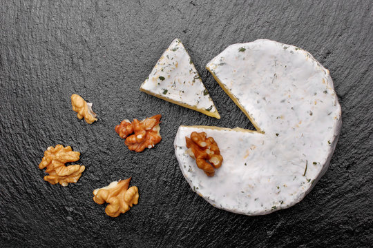 Camembert cheese with nuts on dark slate background.top view