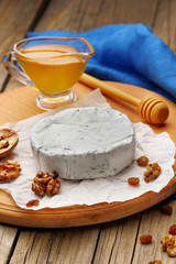 Camembert and brie cheese on wooden background with nuts spices and honey. Italian food.