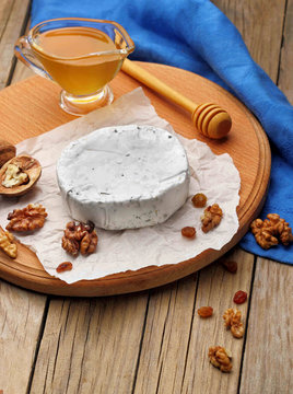 Camembert and brie cheese on wooden background with nuts spices and honey. Italian food.