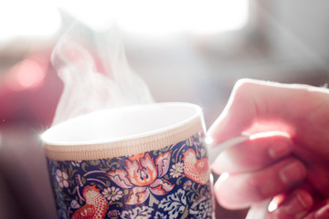 Dampfende Teetasse mit Muster gehalten von Männerhand