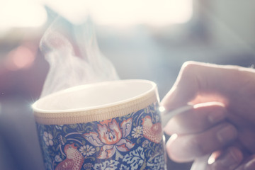 Dampfende Teetasse mit kunstvollem Muster gehalten von Männerhand