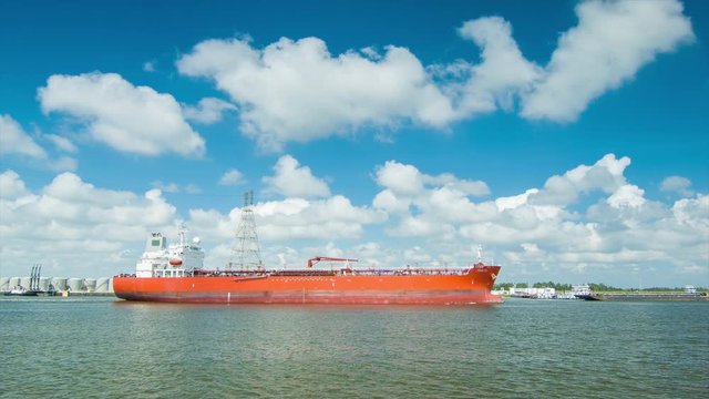 Generic Orange Oil Tanker Freighter Sailing in the Houston TX Ship Channel from the Industrial Refineries towards the Gulf of Mexico on an Idyllic Day with White Clouds in a Blue Sky