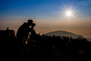 Fototapeta na wymiar silhouette of photographer taking photo at sunrise in a beautifu