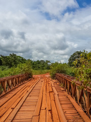 Fototapeta premium Dodgy wooden bridge with timber planks and old iron rails crossing river in Gabon, Central Africa