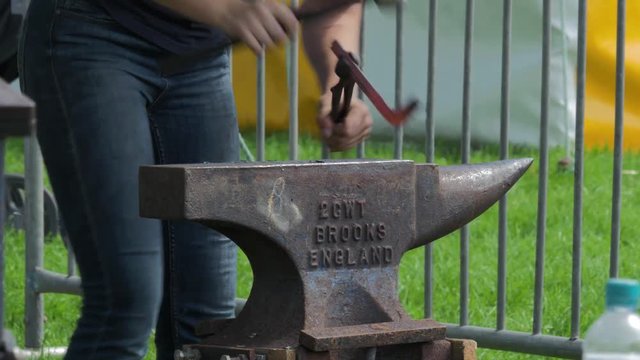 Farrier making horse shoes with hammer and anvil at country fair