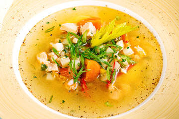 soup with fish and vegetables served on a white round plate