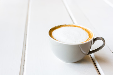 A cup of cappuccino on white table