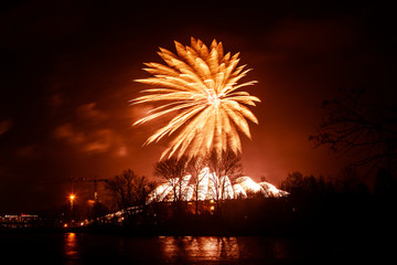 Abstract, blurry, bokeh-style colorful photo of fireworks above the river in New Year