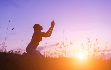 Silhouette of woman praying over beautiful sky background