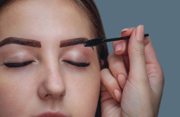 Master makeup corrects and gives shape to pull out with forceps previously painted with henna eyebrows in a beauty salon. Professional care for face.