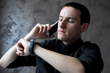 Young man on the phone watching his watch