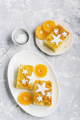 Two servings of homemade juicy mandarin biscuit with asterisks from icing sugar on a dark background. Top