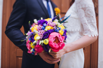 Bride and groom holding wedding bouquet together, outdoor. Love.