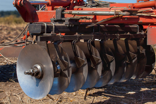 Part of the cultivator steel round discs in a row. Close-up. The work of agricultural machinery.