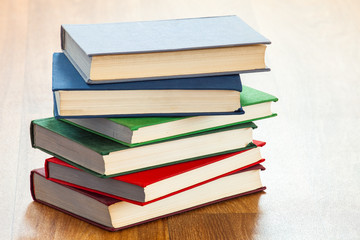 the lying multi-colored books on a wooden table.