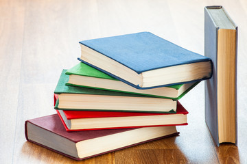 the lying multi-colored books on a wooden table.