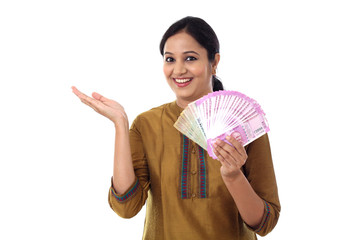 Happy young woman holding 2000 rupee notes against white