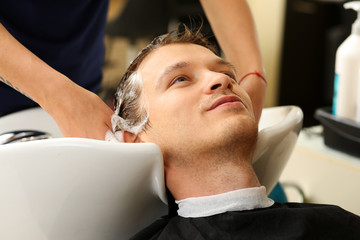 Female hands washing hair to handsome smiling man