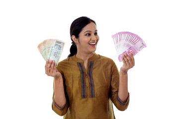 Young woman holding Indian 100 and 2000 rupee notes against white background