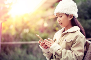 Asian winter child girl looking to mobile phone stay outdoor at