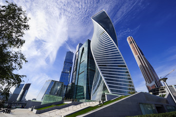 Skyscrapers, modern business office buildings in commercial district, architecture raising to the blue sky with white clouds, bottom view