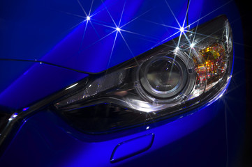 Headlight and hood of powerful sports blue car with stars on bodywork, isolated on black
