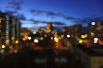 Blurred summer evening city buildings lights, window view background