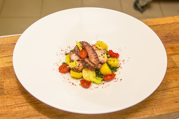 Potato salad with octopus and sun dried tomatoes lies on the pla