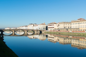 View of Arno river embankment with architecture and buildings and bridge reflecttions on water