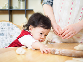 Fototapeta premium Adorable baby girl making gyoza with mom