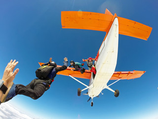 A group of skydivers friends jumping from the orange plane