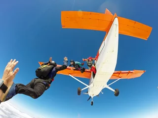 Foto op Canvas A group of skydivers friends jumping from the orange plane © Mauricio G
