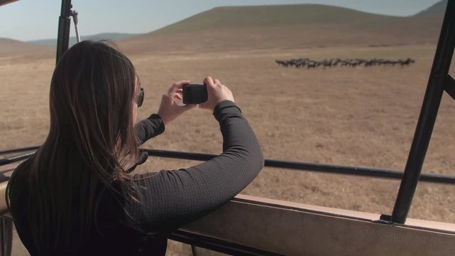 CLOSE UP: Smiling girl photographing game animals in herd in African savannah