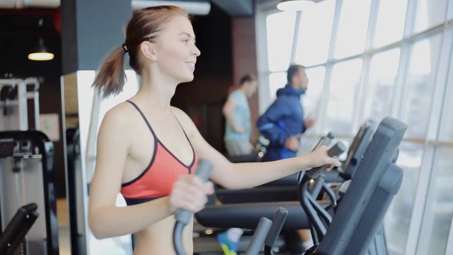 Sporty girl running on running exercise machine in modern at gym
