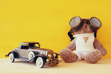 vintage toy car and cute teddy bear on wooden table