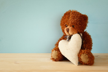 Cute teddy bear sitting and holding a heart