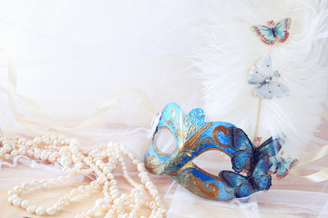 blue venetian mask next to pearls