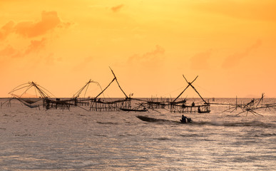 Fototapeta premium Silhouette of traditional fishing method using a bamboo square dip net with sunrise sky background,livelihoods of fishermen at Pakpra, Phattalung in Thailand