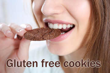 Young woman eating biscuit. Text GLUTEN FREE COOKIES on background