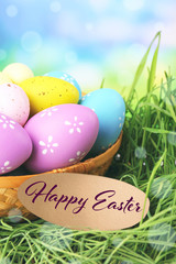 Wicker basket with Easter eggs on green grass