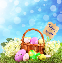 Wicker basket with Easter eggs on green grass